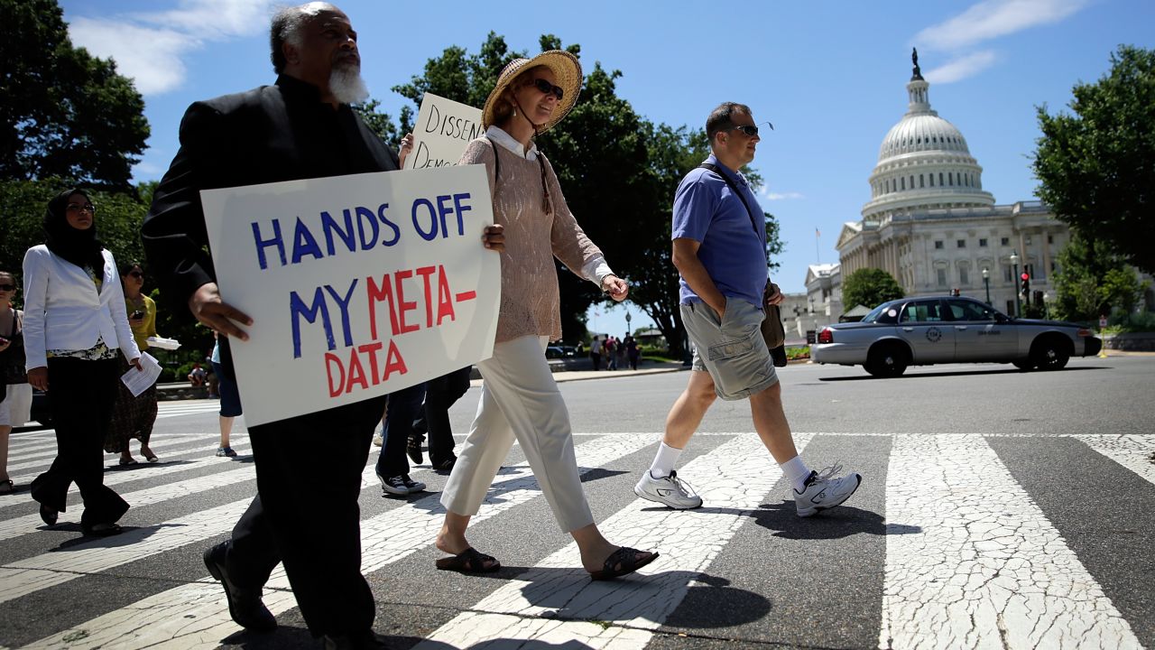 People are walking on a protest with a poster 'HANDS OFF MY META-DATA'