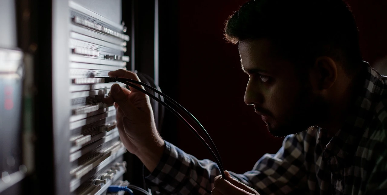 A man unpluging the wire from a server station
